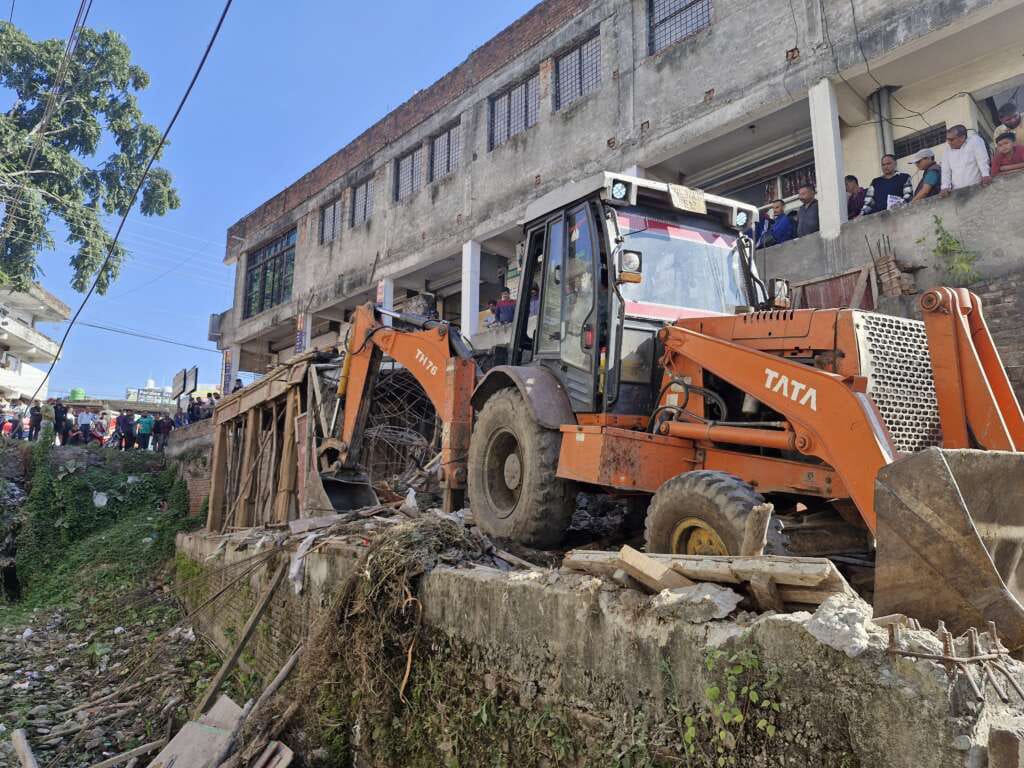 ऊंचापुल में नाले की दीवार से अतिक्रमण ढहाता प्राधिकरण की जेसीबी।